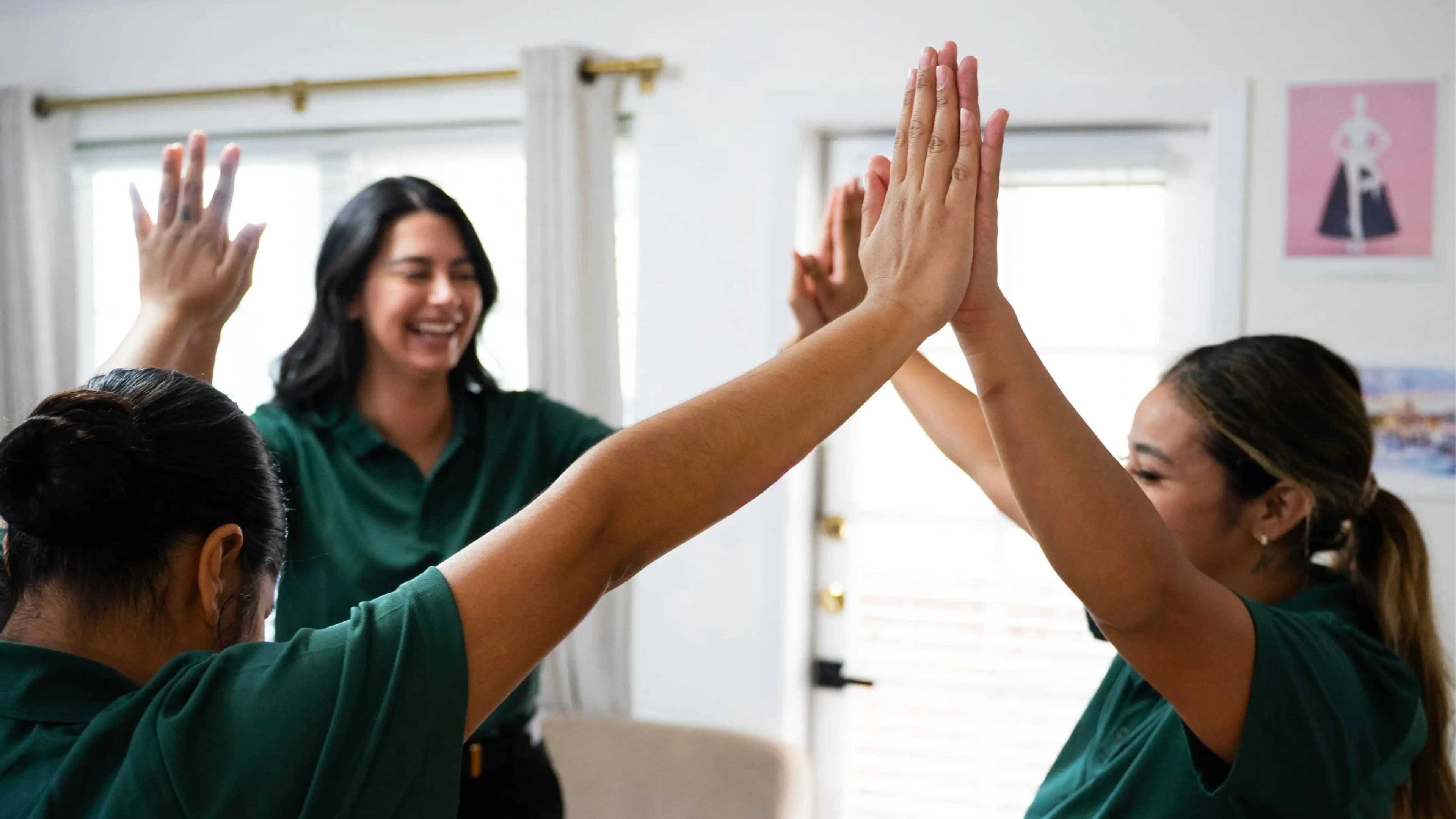 The Silvia's Cleaning team in their green uniforms, sharing a high five